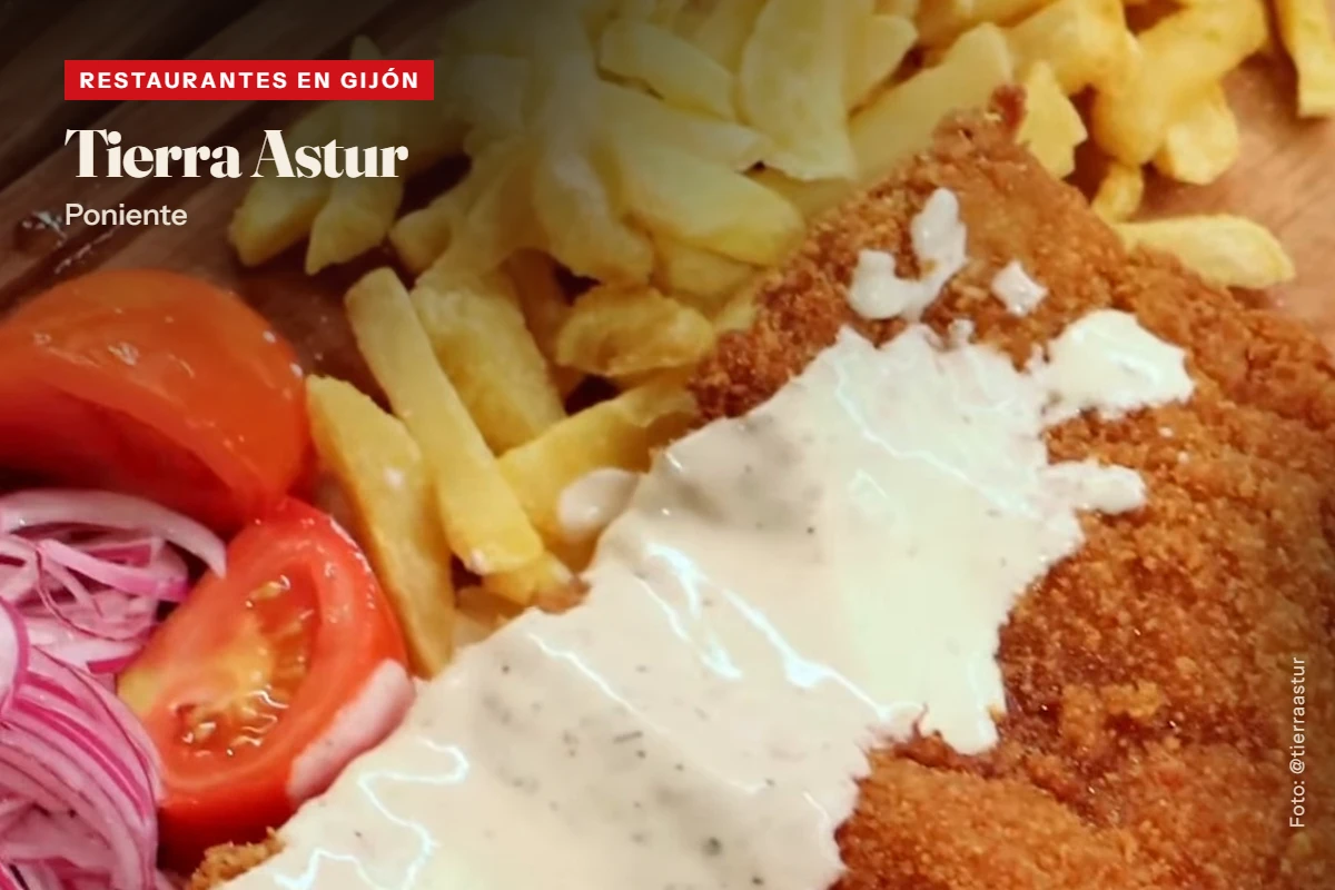 Cachopo de Tierra Astur con salsa de queso por encima, patatas fritas, tomate y cebolla morada